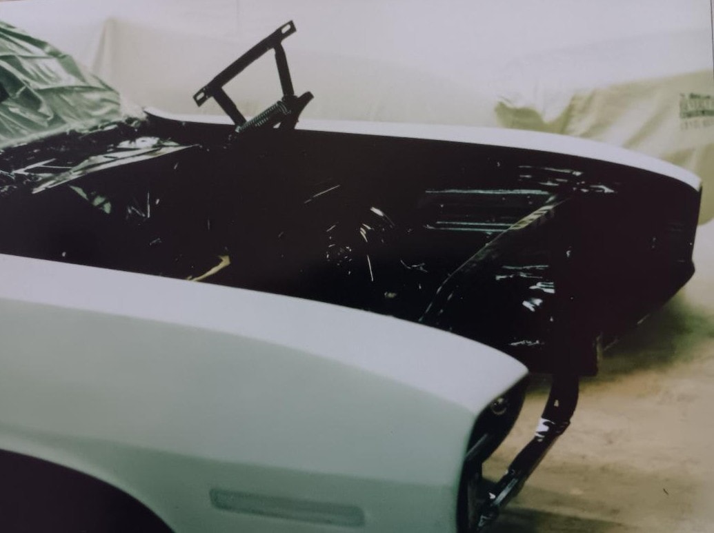 Engine bay receiving fresh TX9 black paint — shaker hood assembly in the background, masked and ready for color