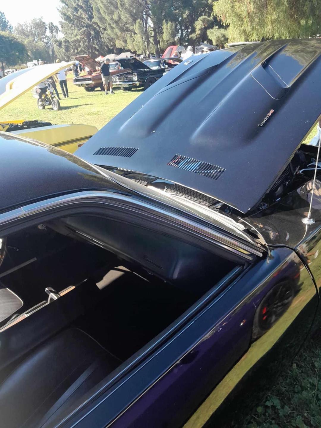 The Phantasm II movie car at a car show — hood open, purple Challenger alongside
