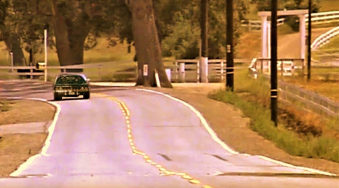The Cuda driving along a tree-lined rural road